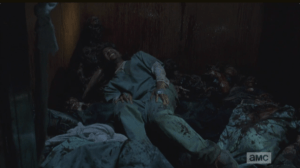 In his struggle to escape the walker's clutches, Noah's grip slips, and he fells long and hard on a heap of bodies, injuring his leg.