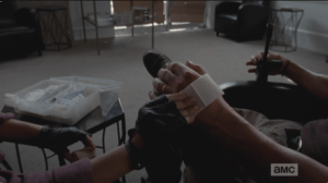 The next shot shifts us back to the present, with Abraham's hand being tended to by Rosita.