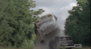 ...then, the front driver's side wheel flips up over an abandoned car in the road, sending the bus flying and landing hard, screeching and smoking, on its right side...