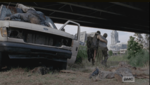 Daryl and Carol lean on each other as they help each other walk away from the totaled van and scattered walkers.