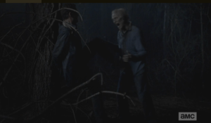Aaron, hands still tied behind his back, braced against a tree trunk, kicking at a walker.