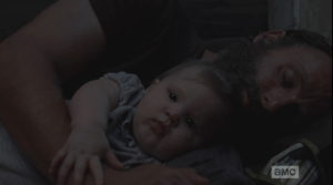 Maggie looks into Baby Judith's sweet face. The baby is awake, but seems to know to let her dad sleep a little longer...Rick, once again, is looking like the hottest single dad ever, sleeping, holding his baby girl.