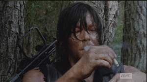 After taking a couple of long drags off the cigarette, Daryl takes the lit end and presses it into his hand.