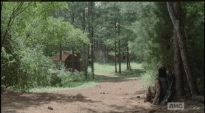 He sits against a tree, looking at the barn.