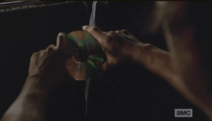 During this exchange, Glenn, sitting in the very back of the van, is looking at his reflection in a cd, turning it this way and that, warping the reflection of his face. He has been very quiet.