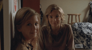 The camera pans up to the girls' faces, and we see Mika, and Lizzie, looking down at Mika's bloodied shirt, with bemused smiles, before looking up at the camera.  Both girls have blood on their faces from their head wounds. They are smiling, serene. Looking into the camera, smiling,  Mika says, 