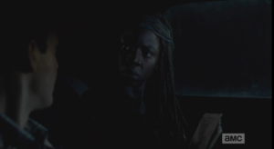 Michonne, alarmed, looks up, asks Aaron why he doesn't have any pictures of his people?