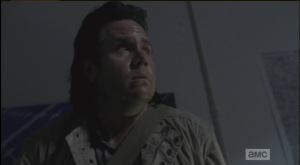 Eugene looks over at the door, the walkers pawing at the windows, trying to get at them.