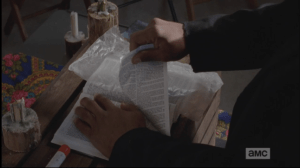 Gabriel turns back to the altar, and the bible before him. The top page has a tiny tear at the top of it, and Gabriel slowly tears the page out of the bible, and tosses it aside.