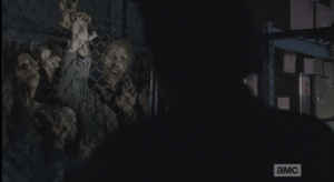 A sizeable group of walkers, locked behind chainlink gated doors. The walkers begin to get loud and agitated as they see, and smell, the living.