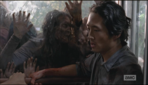 Glenn tries to think of a way as the walkers paw and push,  trying to get at them.