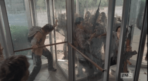 In the center sections, Nicholas braces himself, alone, in one enclosed middle section, while Noah and Glenn are together in the opposite enclosed middle section, with swarms of walkers on both sides, outside and in.
