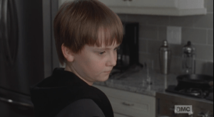 As Carol does her best to try to be mean and run the young boy off, Sam just looks off sadly in the kitchen. It seems like he is used to people being mean around him.