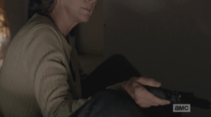 Carol holds out another handgun to Rick, and after a moment, he takes it.