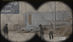 Peering through binoculars, Daryl and Aaron spot a couple of tractor trailers which look promising for a major food score.