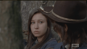 Enid looks at Carl, says nothing. She seems to want to tell him, but then, the telltale snarl of walkers approaching interrupt their sweet moment.