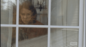 Looking out a window, Maggie watches Gabriel take his priest's frock off the clothesline.