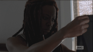 Michonne gets out of bed, walks over, and picks up Noah's shirt, looks at it a long moment.