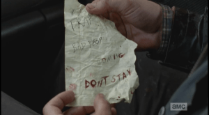 As Aaron and Daryl look around the car for something to cover the windows with, Aaron finds a crumpled note, saying,