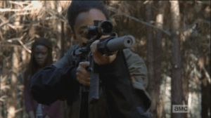 Sasha lifts her rifle and peers through the scope as Michonne looks on dubiously...