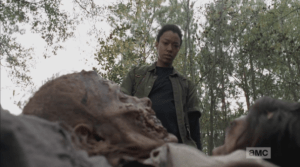 Sasha looks down at the bodies in the pit, then turns and tugs at the body on her cart...the body is stuck, and is hard to dislodge, and Sasha herself slides into the pit with the dead walkers.