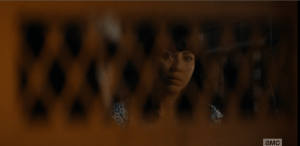 Liza looks at Travis as he surveys the situation outside, asks softly,