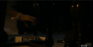 Alicia sees the box of shells on the floor, under the dining room table. She quickly gathers up the shells, scooping them back into the box.