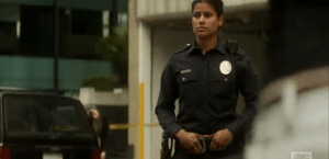 We see a lone female officer standing at her post, with a figure emerging from behind, shuffling towards the officer...