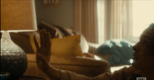 Nick puts a hand up to placate his sister's fury as he backs down towards the floor. 