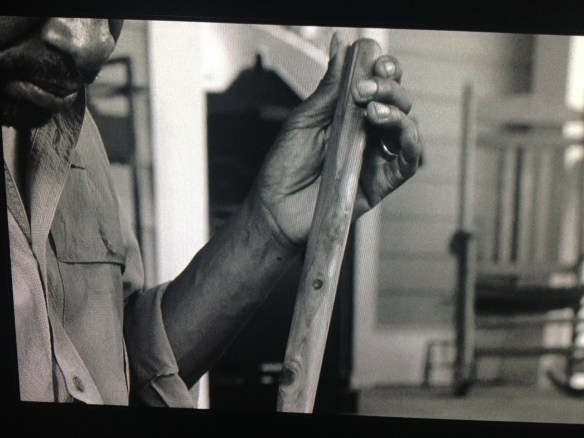 This scene shifts to the past, where Morgan sits outside on Rick's porch, polishing his staff.