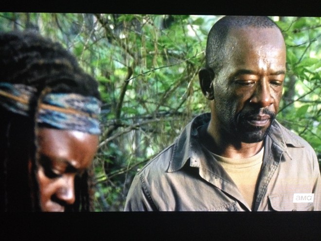 Michonne steps forward. They look down at the dead young man who lay at their feet.