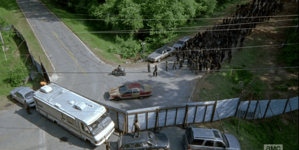 The scene shifts, and we see it's the moment of truth...Daryl is leading the horde to the corner pocket...will the barrier they built hold?